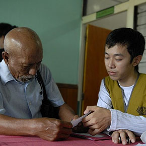 Volunteer Eko (right) explains the direction of using medicine and the home care instruction to Samsuri (left), a surgery patient’s husband. (Photo by Anand Yahya; date: 10/29/2010; location: Kota Singkawang, Indonesia)